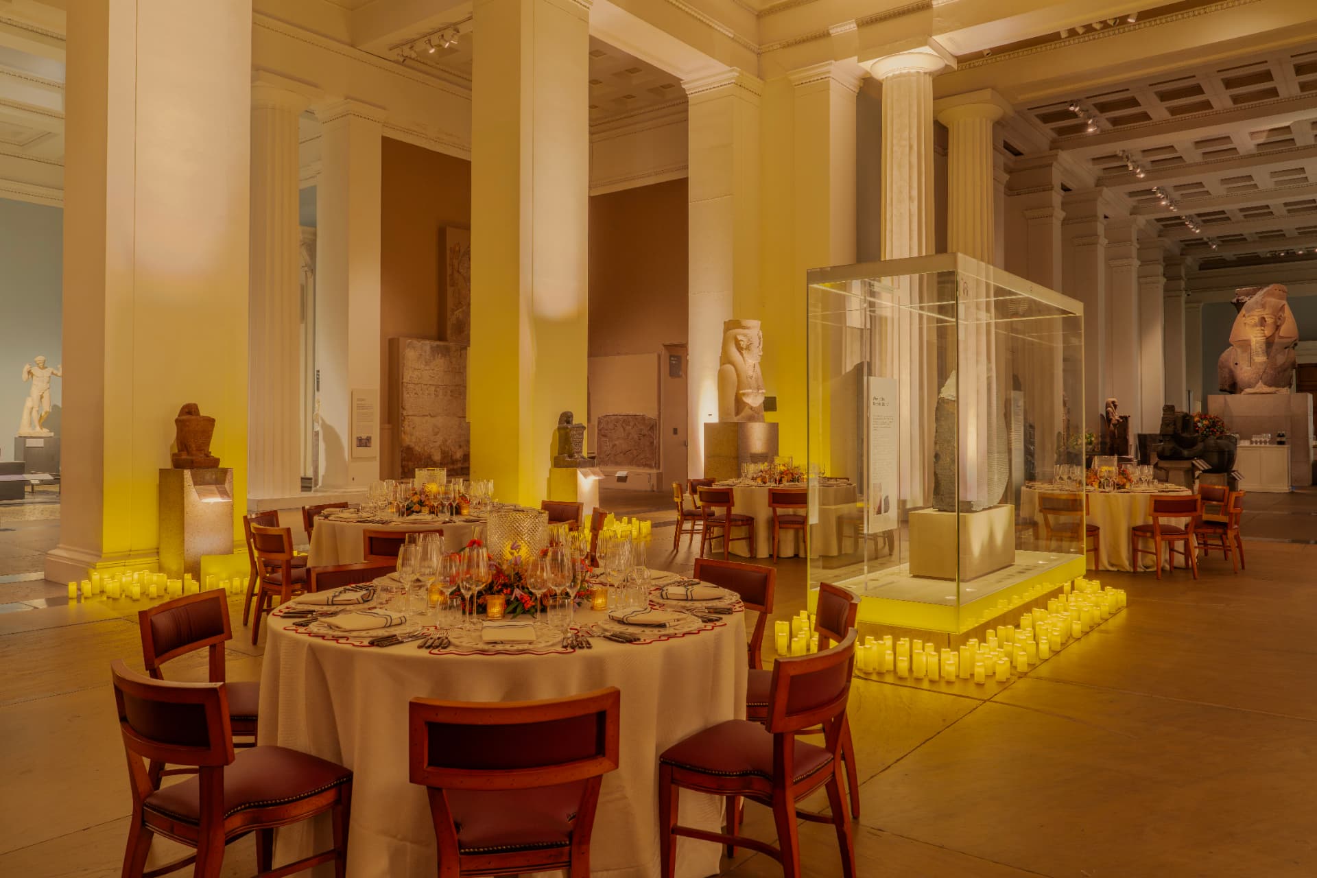 Candlelit dinner tables set among Egyptian sculpture in the British Museum galleries