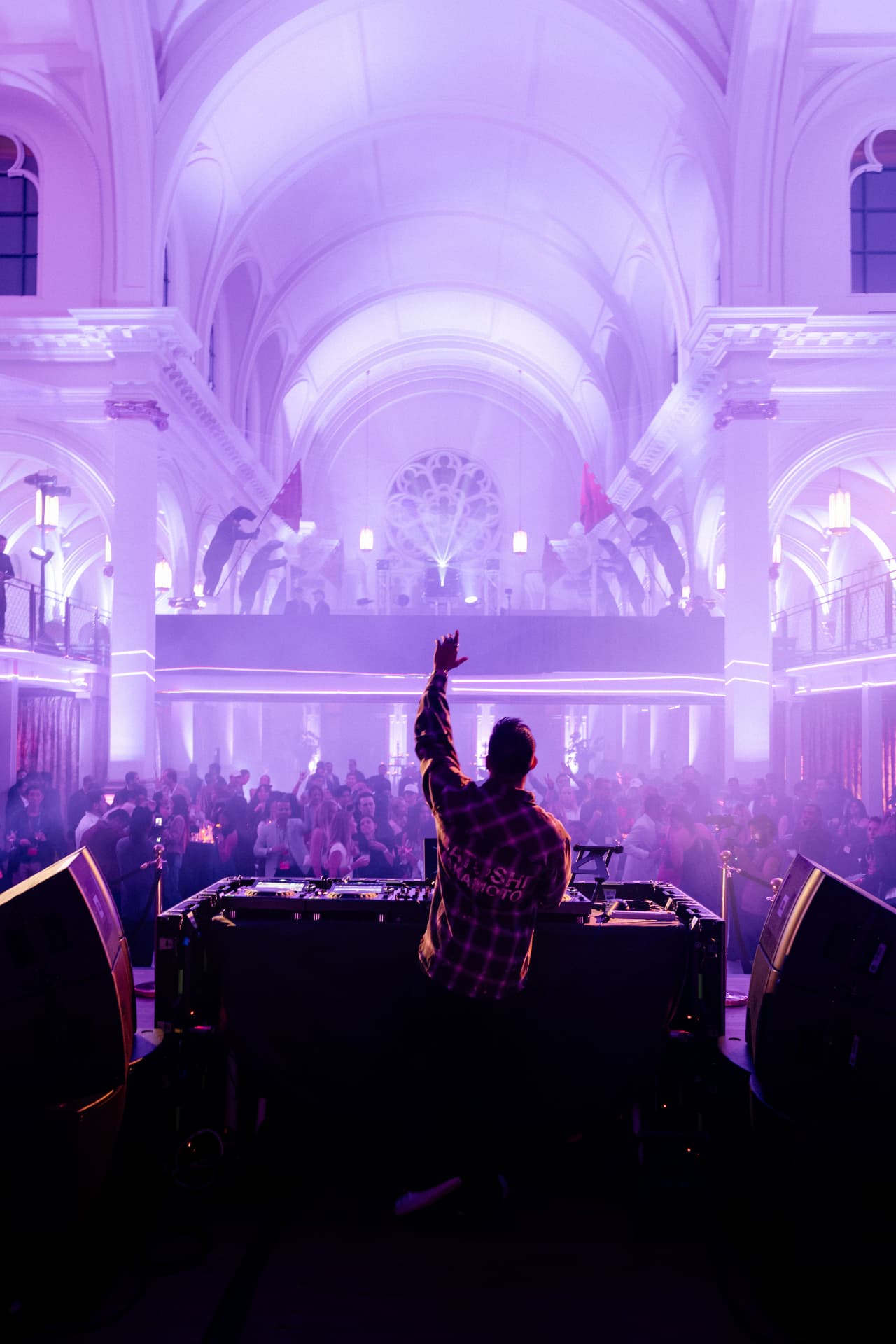Guests and a DJ beneath the vaulted ceiling of a former church lit in violet during Deel After Dark